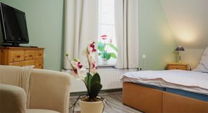 Hier finden Sie ein weiteres Doppelbett mit Nachttischschränkchen und -lampen. Ein Kleiderschrank und eine Kommode bieten Stauraum für Ihre persönlichen Sachen. Auch an eine kleine Sitzecke mit 2 Sesseln, Kinderstuhl, Tischchen und Flachbild-TV ist gedacht.
Der Raum ist mit Laminat und Teppichen ausgelegt, das Fenster verfügt über Verdunklungsvorhänge.